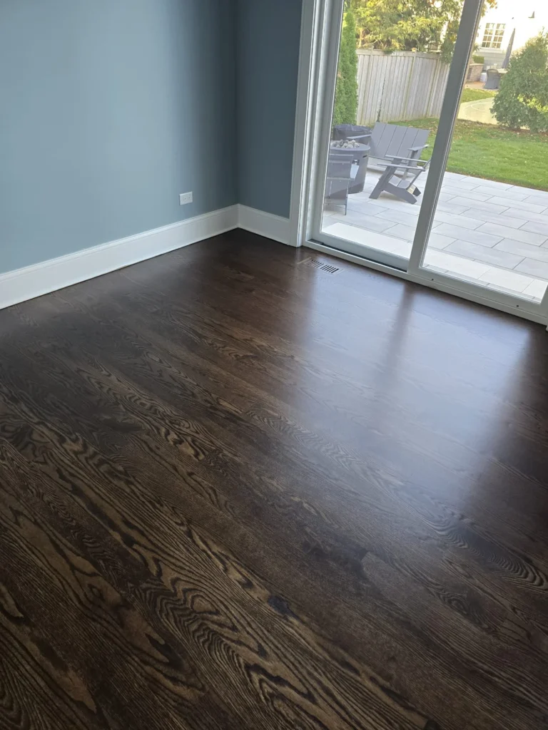 Refinished dark hardwood flooring next to patio doors in Chicagoland home