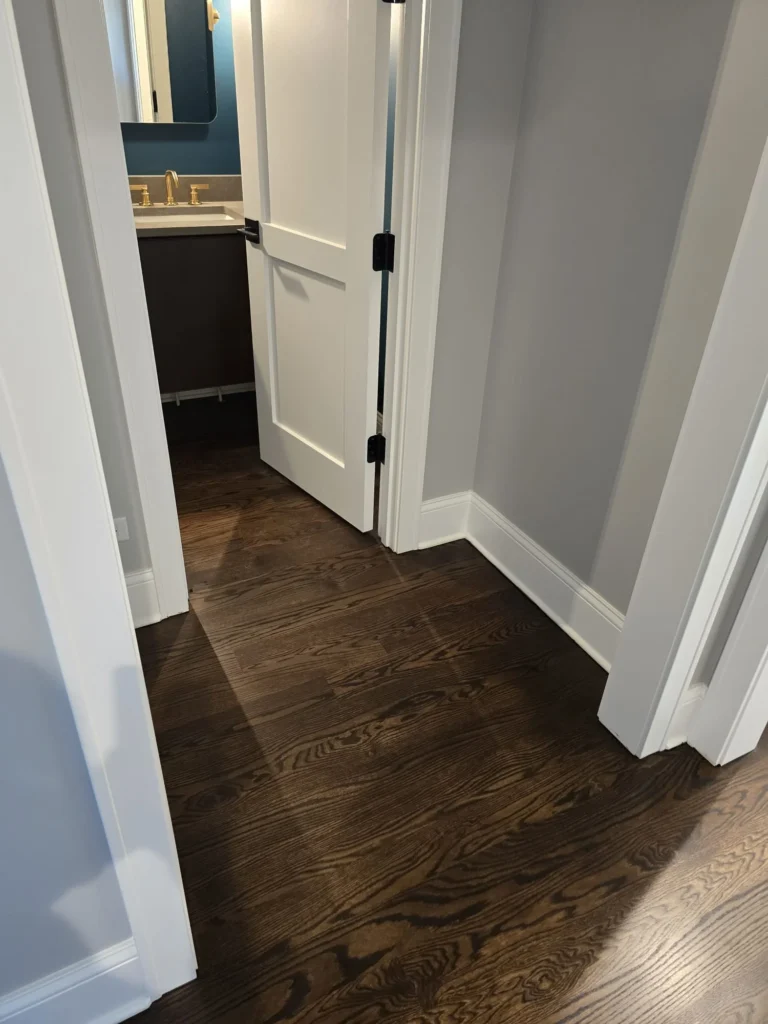 Dark stained hardwood flooring refinished in hallway and powder room