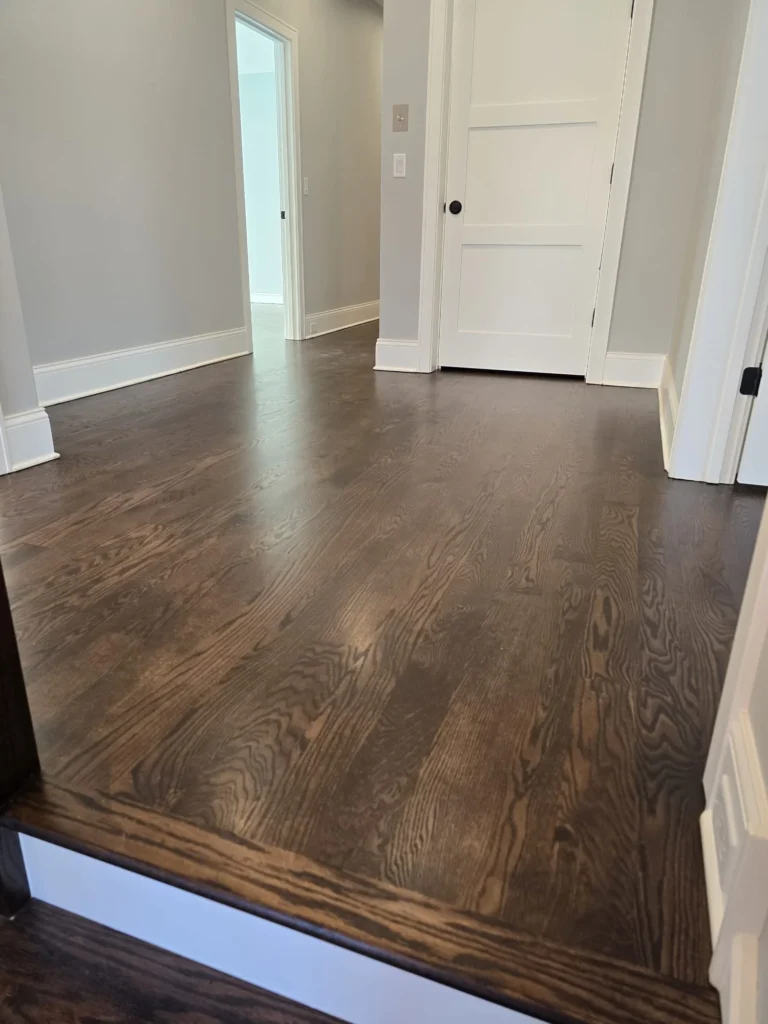 Dark stained hardwood flooring refinished at top of staircase and hallway